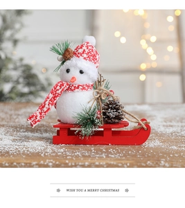 Close-up of a festive snowman ornament with a red fabric hat on a wooden sled base