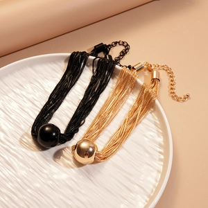 Detail of multi-layered metallic necklaces with polished round beads in gold and black