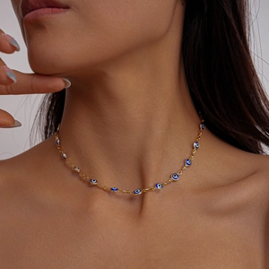Close-up of gold chain necklace featuring blue evil eye enamel charms on woman neck