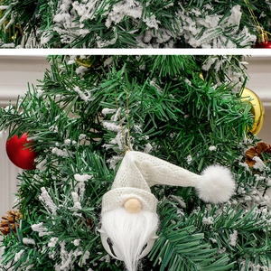 Close-up of a white knitted Christmas gnome ornament with a bell on a decorated tree