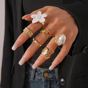 Détails d'un lot de 6 bagues dorées avec fleurs blanches, perles et pierres précieuses