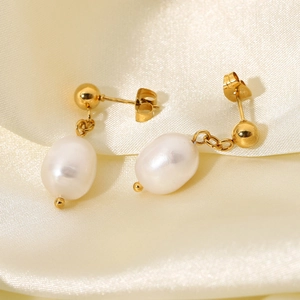 Macro detail of natural white baroque pearl drop earrings with polished gold ball studs