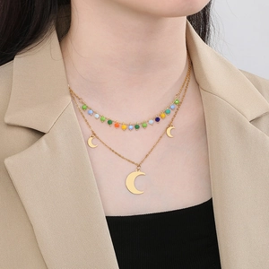 Double-layered gold necklace with colorful beads and moon pendants on a female model