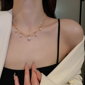 Detail of layered gold beaded necklace with five elegant white pearl charms on model