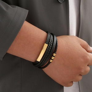 Close-up of men's multi-layer braided leather bracelet with gold metal accents on wrist