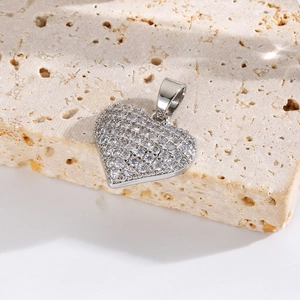 Macro shot of silver heart pendant with shimmering pave-set crystals on a textured stone