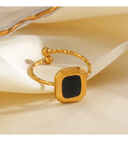 Macro shot of gold square ring with black enamel on elegant cream silk background