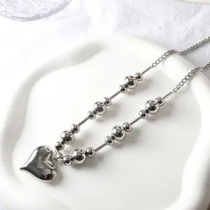Detailed close-up of 18k gold plated steel bead necklace with 3D heart pendant