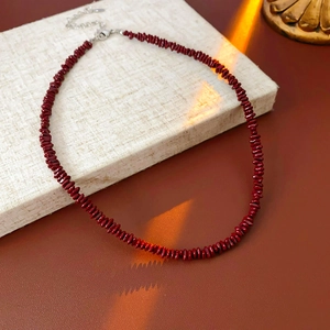 Detalle de collar de cuentas rojo oscuro con cierre de mosquetón plateado y cadena ajustable