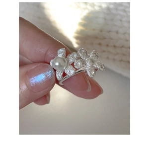 Detail of silver twig texture ring with white pearl on a finger with blue nails