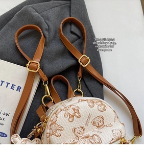 Détail du mini sac à dos beige en similicuir avec motifs ours et boucles dorées