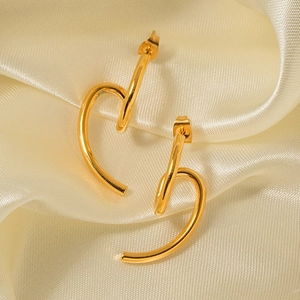 Detail of 18k gold plated geometric earrings on elegant beige silk fabric texture