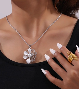 Dettaglio della collana a corda d'argento con fiore di perla e anello a serpente d'oro