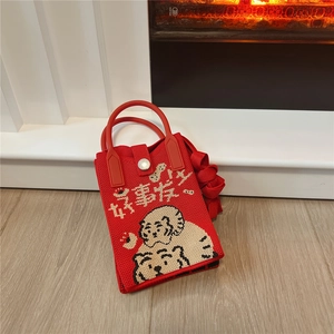 Detail of red knitted mini bag with festive cartoon tigers and lucky text embroidery