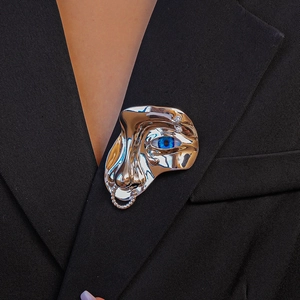 Broche visage artistique argentée avec oeil bleu et chaîne sur veste de costume