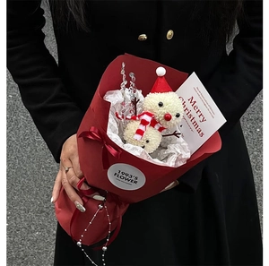 Detail of Christmas snowman bouquet held by hand featuring red wrapping and festive ribbons