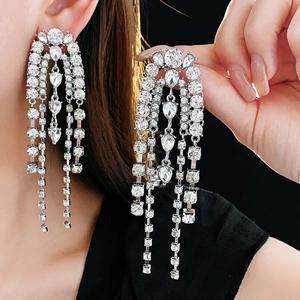 Close-up of elegant long silver tassel earrings with tiered crystal stones on ear