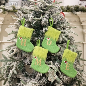 Detail of four green knit Christmas stockings with gold HOME letters on snowy tree