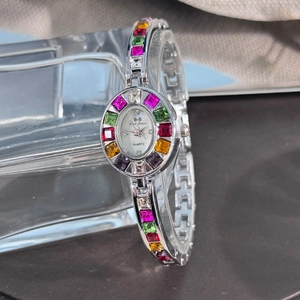 Macro shot of silver quartz watch featuring colorful crystals on the oval bezel and bracelet