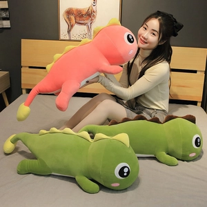 Pink and green dinosaur plush toys displayed on a cozy bed with a female model