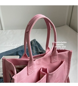 Dettaglio ravvicinato della borsa tote in tela rosa con manici rinforzati e tessuto robusto