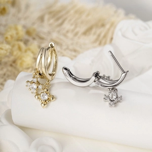 Elegant gold and silver cross earrings with zircon tassels on white fabric background