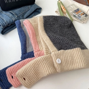 Close-up of knit Balaclava hats in blue, pink, beige, and grey with button detail