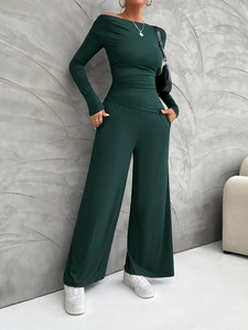 Detail of dark green long sleeve top and wide leg pants set in a stylish room interior