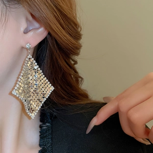 Close-up of golden mesh rhombus drop earrings with sparkling rhinestones on model