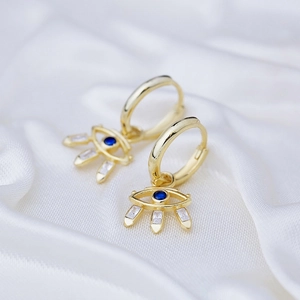 S925 silver needle evil eye drop earrings with blue stone and gold plating on white silk