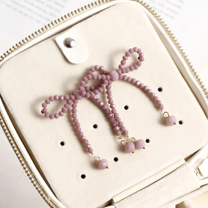 Detail of pink crystal beaded bow earrings with drop beads in a cream jewelry box