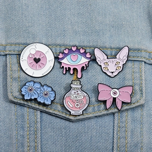 Dettaglio di sei spille in smalto pastel goth con design a bulbo oculare su denim