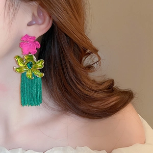 Gros plan de boucles d'oreilles fleur rose avec pompons verts sur mannequin