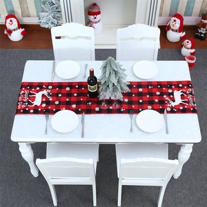Detail of red and black buffalo plaid Christmas table runner with white reindeer pattern