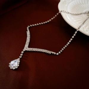 Detail of silver V-shape necklace with teardrop rhinestone on elegant red silk
