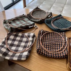 Detailed collection of vintage plaid wool crossbody bags with leather straps on a wooden table