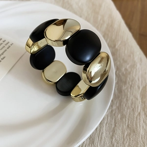 Detail of vintage acrylic oval beaded stretch bracelet in matte black and polished gold finish