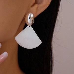 Macro shot of silver fan-shaped geometric drop earrings with brushed and polished metal finish