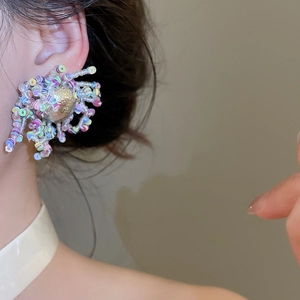 Detalle en primer plano de pendientes de flores con cuentas de colores y lentejuelas arcoíris.