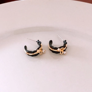Detail of 18k gold plated C-shaped earrings with black waves and ribbon design