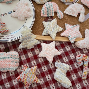Close-up of pastel bouclé yarn knitted Christmas charms for DIY crafts and decorations