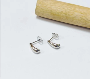 Macro detail of polished silver teardrop stud earrings with a glossy mirror finish