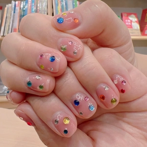 Detalle de uñas rosa brillante con pedrería 3D de colores y gemas mixtas brillantes