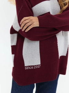 Detailed macro of burgundy knit sweater showing white striped hem and since 2017 text