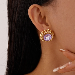 Detailed macro view of retro gold chain link earrings featuring a large purple gemstone