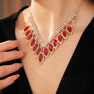 Close-up of elegant gold V-shape necklace with marquise-cut red gem and crystal details