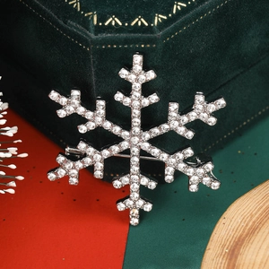 Close-up of a silver snowflake brooch with sparkling rhinestones on green velvet packaging