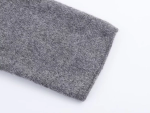 Dettaglio del cappotto di lana grigia che mostra la trama spessa del tessuto e delle fibre