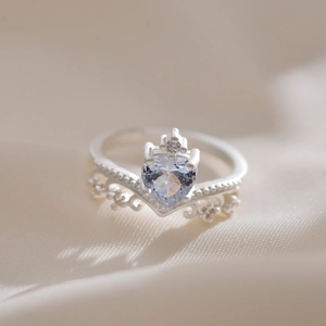 Macro detail showing a silver crown ring featuring a heart-shaped zircon and intricate engraving