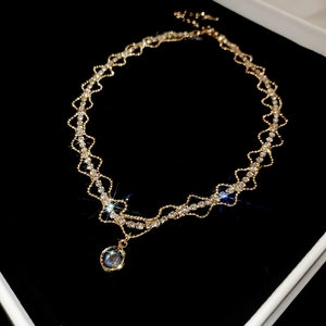 Macro detail of gold wavy chain necklace with pavé diamonds and round pendant